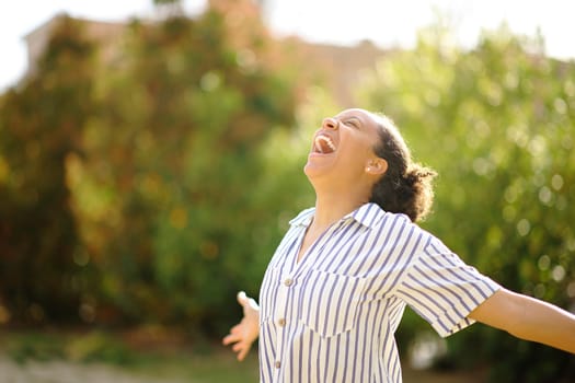 Excited black woman screaming to the air in a park