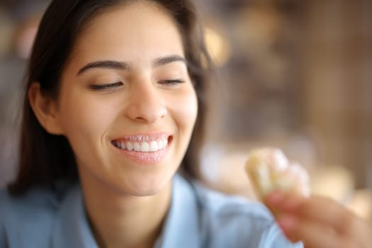 Happy woman eating sweet croissant with dirty lips in a restaurant