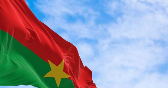 National flag of Burkina Faso waving in the wind on a clear day. Two equal horizontal red and green bands with a yellow five-pointed star in the center. 3d illustration render. Fluttering fabric