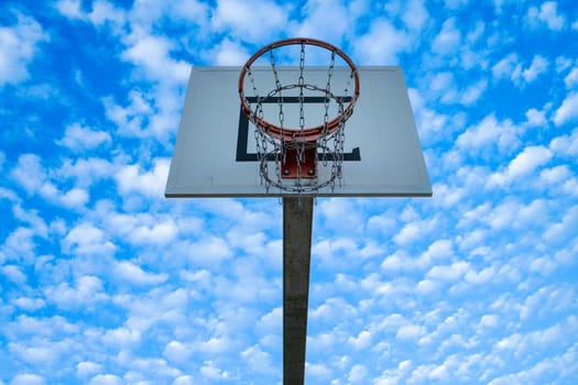 High basketball hoop with blue sky and clouds