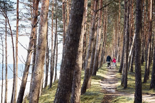 Family walking in forest along seashore. Spending vacations at sea. Summer trip. Enjoying free time. Leisure time close to nature. Travel concept