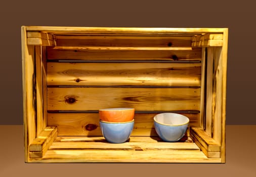 Several ceramic bowls stand very decoratively in a wooden box.