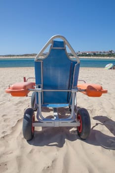 Blue beach wheelchair on sand ready to use. Accessible tourism concept
