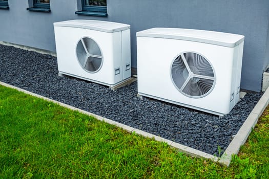 Two air source heat pumps installed outside of new and modern city house, green renewable energy concept of heat pump