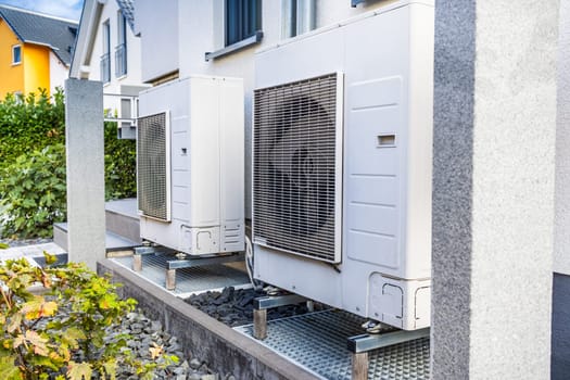 Two air source heat pumps installed outside of modern family house, green renewable energy concept of heat pump