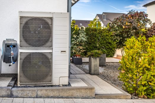 Two air source heat pumps installed outside of modern family house, green renewable energy concept of heat pump