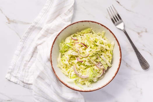 Vegan coleslaw salad made of freshly shredded white cabbage with red onions