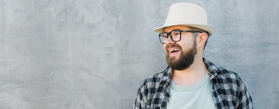 guy tourist looking happy wearing straw hat for travelling, standing against concrete wall background with copy space