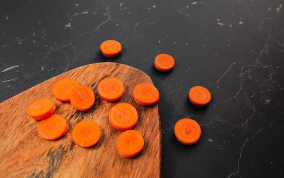 Carrot sliced to small circles on wooden working board.