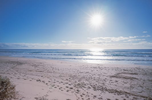Sun rising waves breaking on sandy shore.Conceptual background for summer vacation or business travel. Horizontal panorama banner of sunrise sea sand sky horizon. Inspirational beautiful relaxing scenery of  seashore. Concept holiday on beachfront. Empty beach seascape with copy space.
