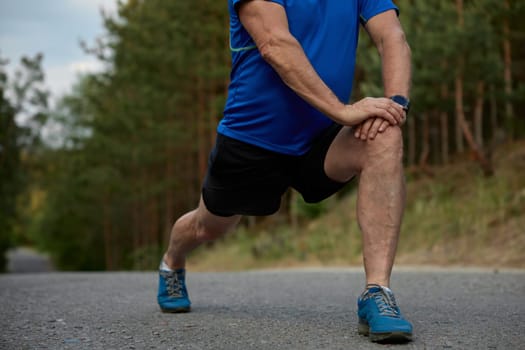 Crop view of mature athlete warming up muscles before running practice. Everyday sport routine for healthcare and wellness on retirement