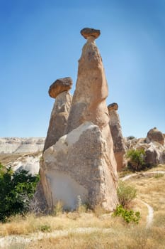 Unique geological rock formations Fairy Chimneys in Cappadocia against blue sky in summer. Popular touristic area in Goreme, Nevsehir, Turkey
