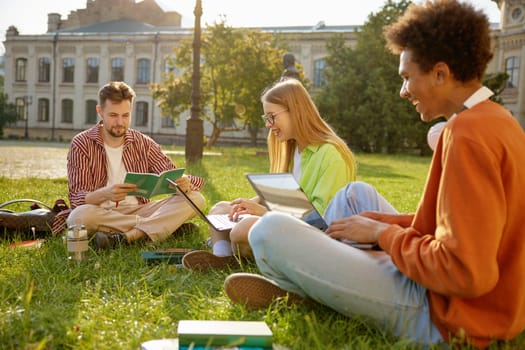 Classmate friends sitting together on green grass at campus park. Student friendship, youth and education concept