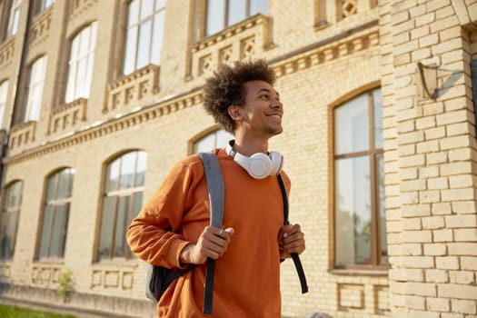 Exited teenage boy student walking among buildings of university campus. Back to offline education process