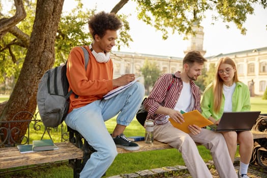 University students working on homework or creative project at campus. Cheerful classmates enjoying fun education process