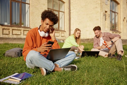 Group of teenager students studying with laptops, learning for exams and communicating sitting on ground at campus. Free academic education