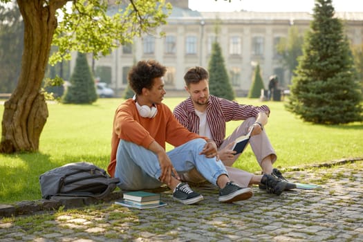 Two young fellow students talking together discussing ideas while preparing for university classes outdoors