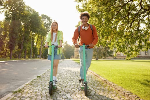Friends students using electric scooter vehicles riding in university park