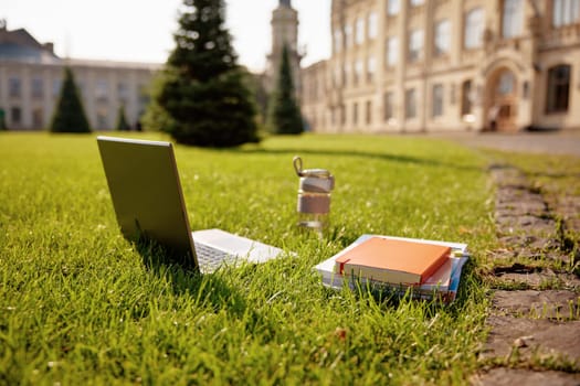 Laptop, note pad and books studying accessories on campus ground. Students supplies prepared for learning
