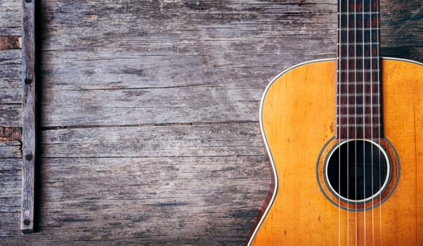 Closeup of old acoustic spanish guitar on rustic wooden background from above. Popular music tune and song design banner. Top view.