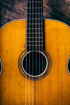 Closeup of wooden acoustic guitar from above. Music vintage background.