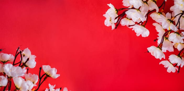 Spring cherry blossom border over red paper background with copyspace. Chinese new year nature design. Flower decor for traditional asian spring festival. Lunar new year celebration.