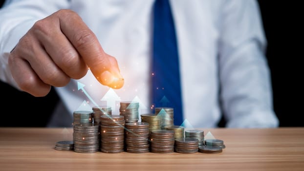 Businessman puts money on pile of coins. Ideas for investing and growing a business, maximizing profits from business, ideas for setting savings goals and setting goals for fixed deposits with banks.