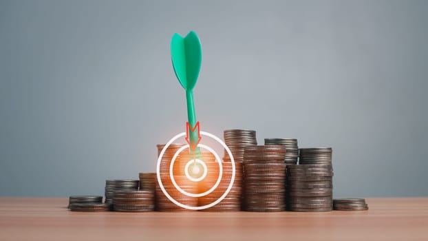 The green arrow hits the target in the center of a row of coins on the wooden floor. Concepts of finance, savings and investment. Business growth concept, finance goals concept.
