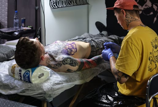 Krakow, Poland -  June 12, 2022: Unidentified  participant at 15th Tattoofest Convention in Cracow. One of the most prestigious tattoo festivals. Tattoo artist at work.