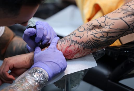 Krakow, Poland -  June 12, 2022: Unidentified  participant at 15th Tattoofest Convention in Cracow. One of the most prestigious tattoo festivals. Tattoo artist at work.