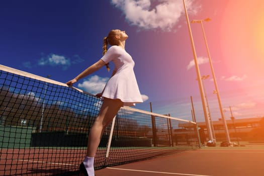 Sexy girl tennis player in white dress and heels holding tennis racket on the court. Young woman is playing tennis, sport