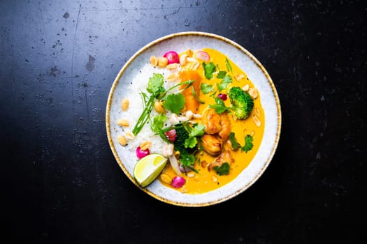 Thai chicken and a peanut curry with rice, dark background, top view. Asian cuisine concept.