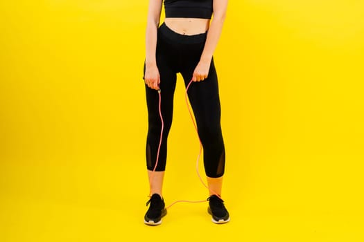 Blond woman with jump rope in a studio, yellow red and dark background