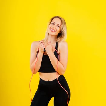 Blond woman with jump rope in a studio, yellow red and dark background