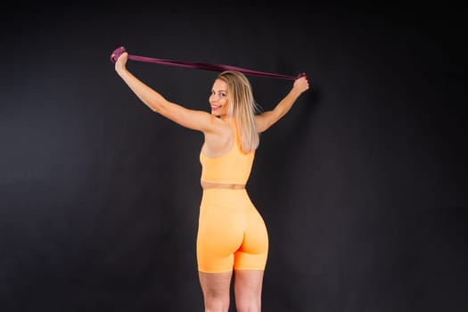 Blond woman with jump rope in a studio, yellow red and dark background