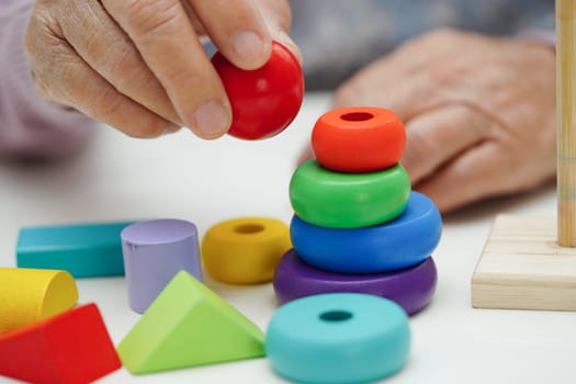 Asian elderly woman playing puzzles game to practice brain training for dementia prevention, Alzheimer disease.