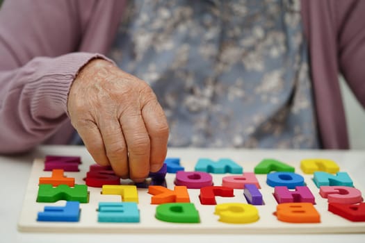 Asian elderly woman playing puzzles game to practice brain training for dementia prevention, Alzheimer disease.