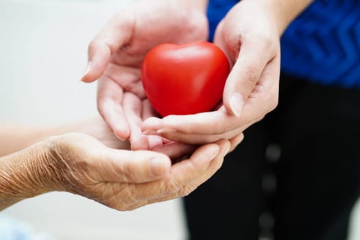Asian young boy give red heart to old grandmother with love and care.