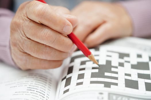 Asian elderly woman playing sudoku puzzle game to practice brain training for dementia prevention, Alzheimer disease.