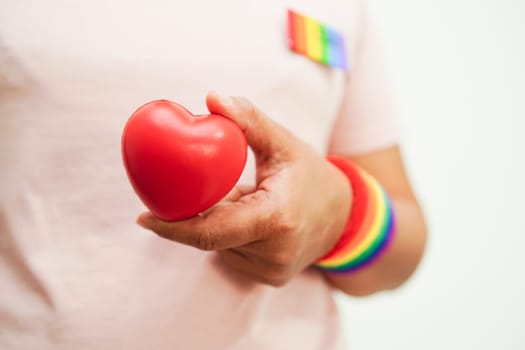 Asian woman holding red heart with rainbow flag, LGBT symbol rights and gender equality, LGBT Pride Month in June.