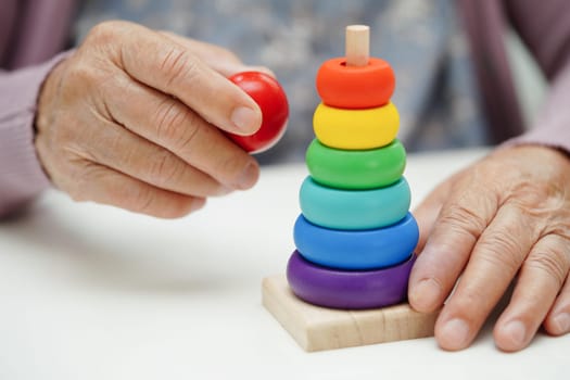 Asian elderly woman playing puzzles game to practice brain training for dementia prevention, Alzheimer disease.