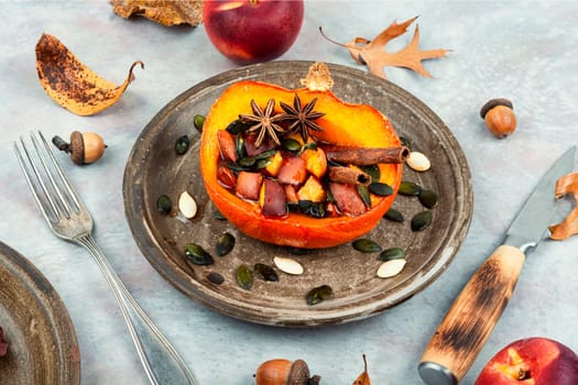 Half orange autumn pumpkin or squash baked with apples, peaches and cinnamon. Dietic autumn recipe