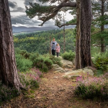 Mother and daughter standing on a viewpoint in Lead mines, with a view on a valley and pine forest. Family hike in Wicklow Mountains, Ireland