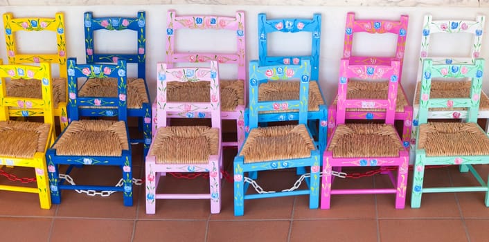 Vila Nova, Portugal - Jul 26th, 2023: Colorful children chairs. Seat made of rush leaves. Alentejo crafts