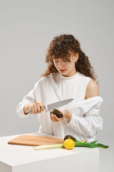 Nutritionist woman cutting fresh avocado into halves. Concept of balanced eating.