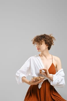 Pretty woman holds a plate with walnuts, hold one nut in hand and looks to the side