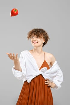 Smiling woman trowing red bell pepper up