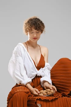 Young woman placed a plate of walnuts on the hem of her skirt and looks at it