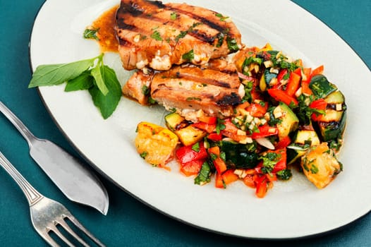 Cooked tuna steak with vegetables on a plate. Seafood.