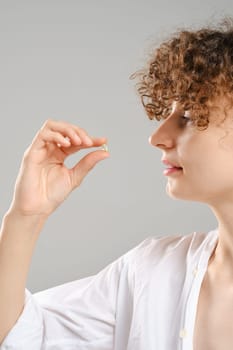 Woman holds pill or vitamin in hand